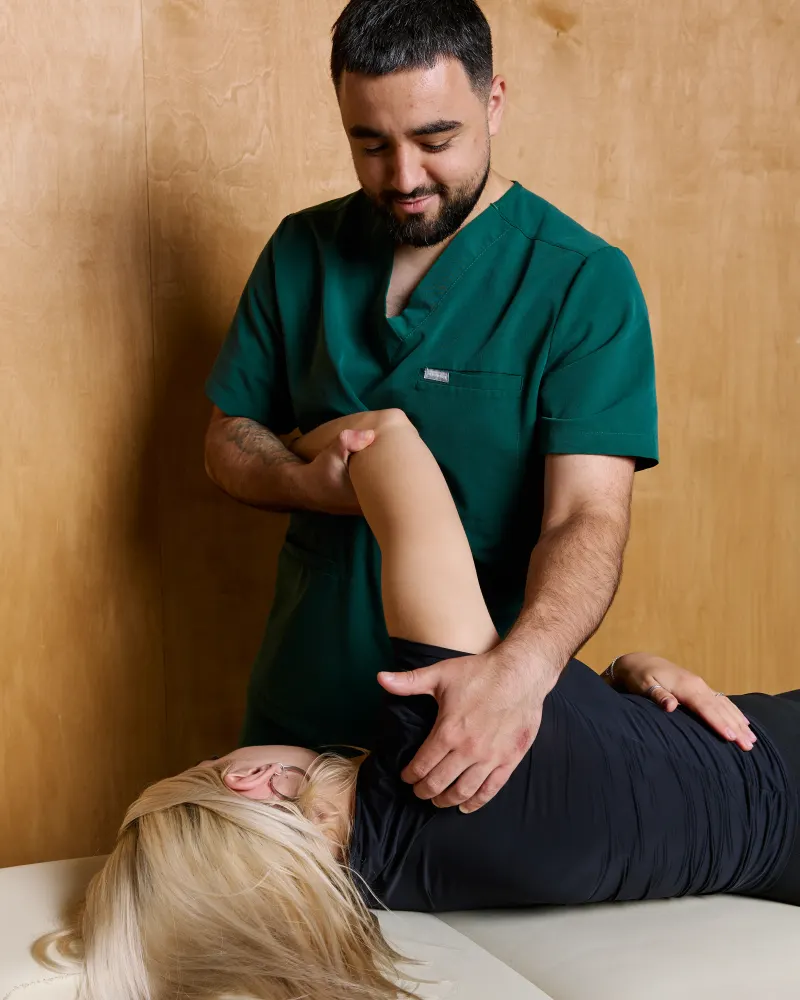 Fizjoterapeuta pracuje z barkiem pacjentki leżącej na stole terapeutycznym
